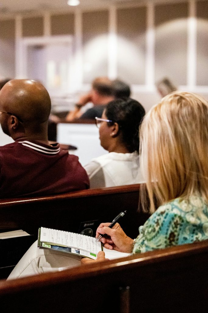 Attendees are seated in a classroom, attentively taking notes during a lesson.