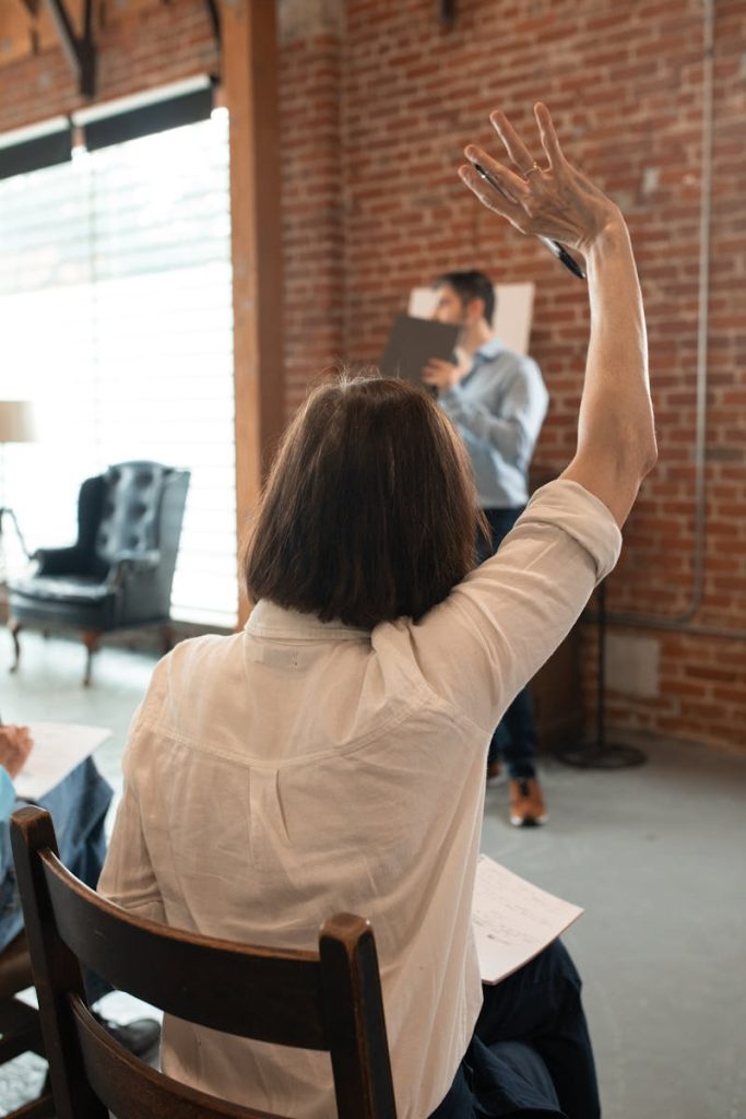 A student in a classroom raising hand to ask a question. Indoor educational environment.